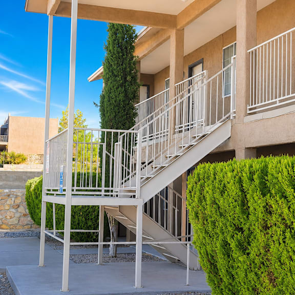 a staircase with a metal railing and a green bush on the side.