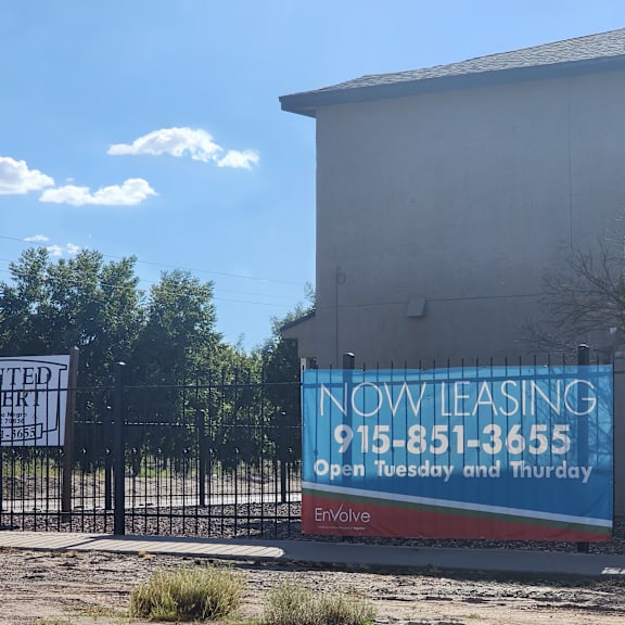 a now leasing sign is posted on the gate of a building