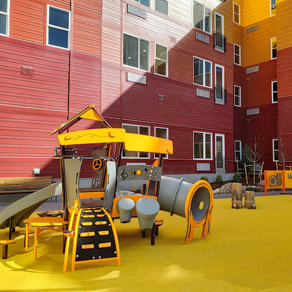 a playground with a yellow slide and orange barriers.