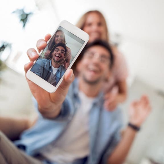 a man holding up a cell phone with his family on it