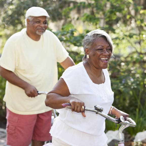an older woman riding a bike with a man walking behind her