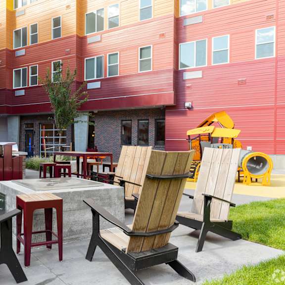 a patio with chairs and a table in front of a building.