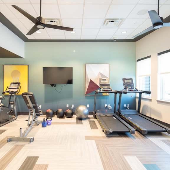 a gym with a variety of equipment including treadmills, exercise bikes, and weights.