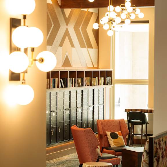 a room with a chair and a table with a lamp on it.