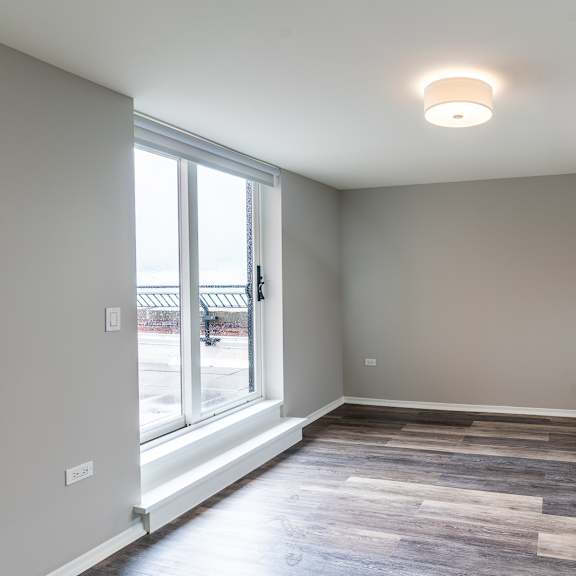 Thumbnail 9 of 14 a living room with a large window and wood flooring at Park Heights by the Lake Apartments, Illinois, 60649