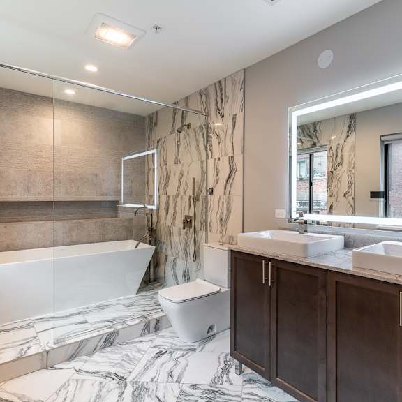 Thumbnail 13 of 14 a bathroom with a tub and two sinks and a mirror at Park Heights by the Lake Apartments, Chicago, Illinois