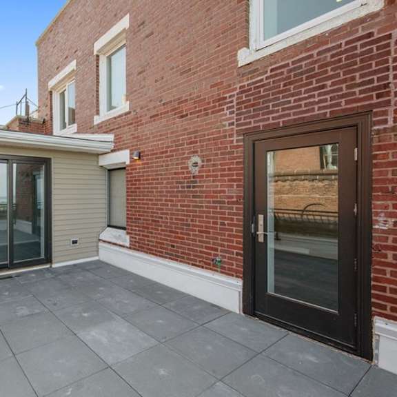 Thumbnail 6 of 14 a patio with a brick wall and glass doors at Park Heights by the Lake Apartments, Chicago, Illinois
