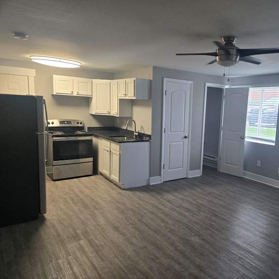 a kitchen with a black refrigerator and a fan on the ceiling.