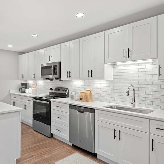 Thumbnail 7 of 18 A modern kitchen with white cabinets and a wooden table. at Indian Creek Apartments*, Cincinnati, OH, 45236