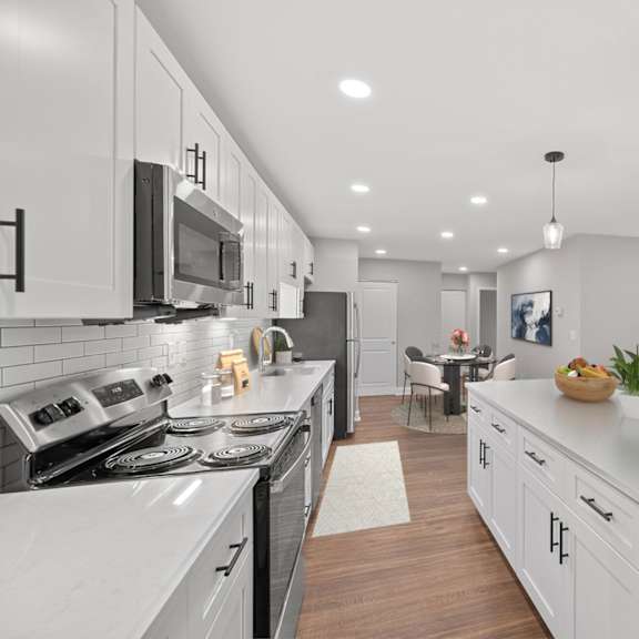 Thumbnail 6 of 18 A modern kitchen with white cabinets and a large island. at Indian Creek Apartments*, Cincinnati, OH, 45236