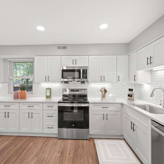 Thumbnail 7 of 25 A modern kitchen with white cabinets and a wooden floor. at Indian Creek Apartments*, Cincinnati, Ohio