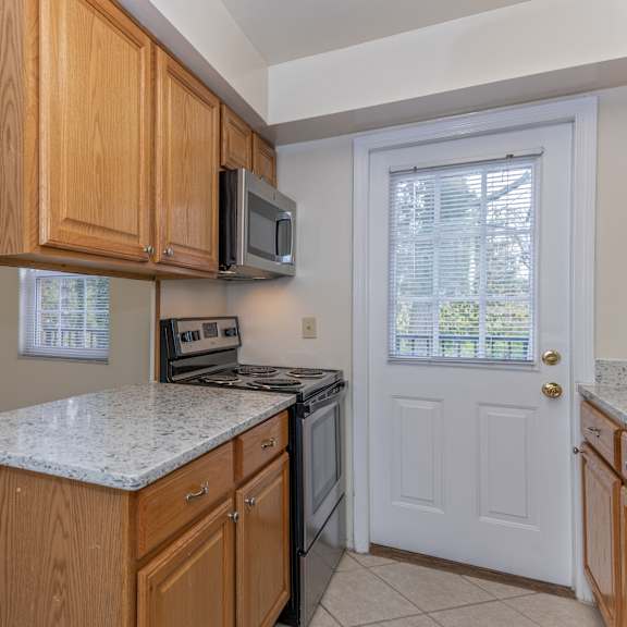 Thumbnail 5 of 22 Kitchen with wooden cabinets and a stove and a microwave at Indian Creek Apartments, Ohio, 45236