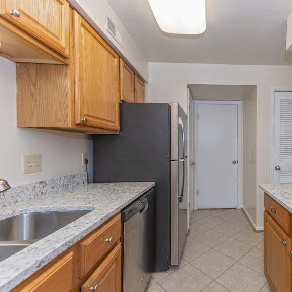 Thumbnail 6 of 22 Kitchen with wood cabinets and granite counter tops and a black refrigerator at Indian Creek Apartments, Cincinnati, OH, 45236