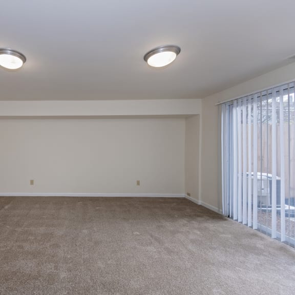 Thumbnail 16 of 21 an empty living room with a large window and carpet at Indian Creek Apartments*, Ohio