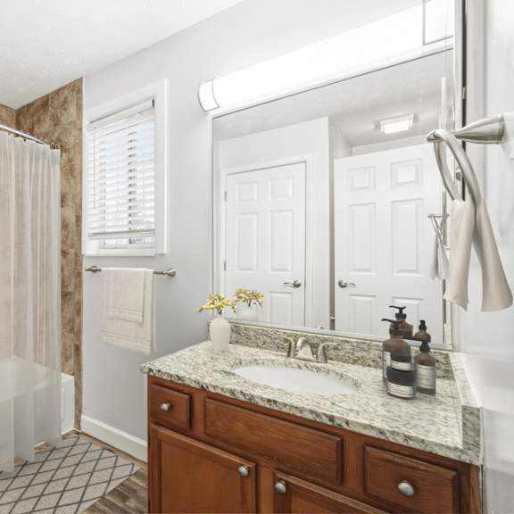 a bathroom with a beige tiled shower and a white sink.