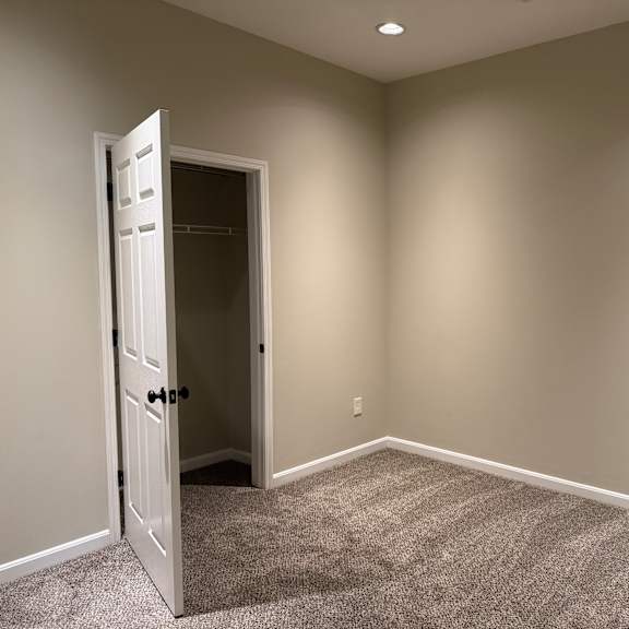 Thumbnail 3 of 10 A room with a carpeted floor and a door open to another room.