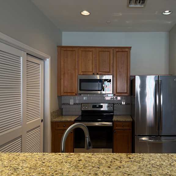 Thumbnail 5 of 10 A kitchen with a refrigerator, microwave, and stove.