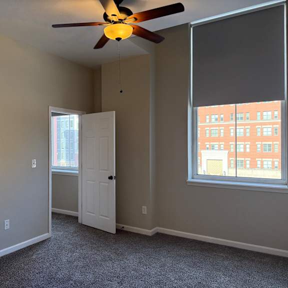 Thumbnail 6 of 10 A room with a ceiling fan and a window.