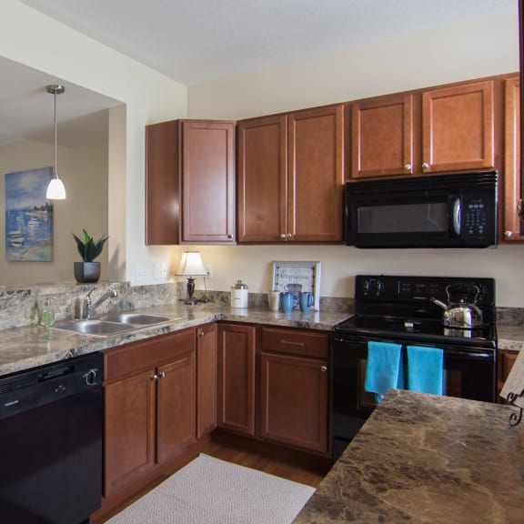 a kitchen with wooden cabinets and granite counter tops  at Grove City Summit, Grove City, OH