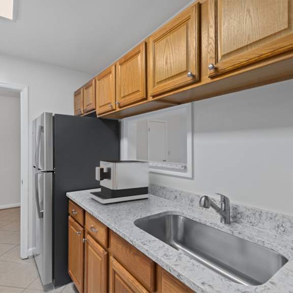 Thumbnail 6 of 12 A kitchen with a black fridge and wooden cabinets.