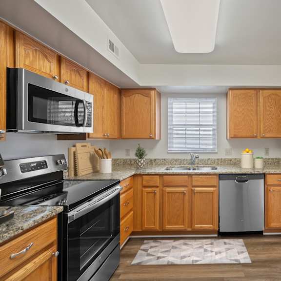 Thumbnail 4 of 10 A kitchen with wooden cabinets and a black stove top oven. at Indian Creek Apartments*, Cincinnati, OH, 45236