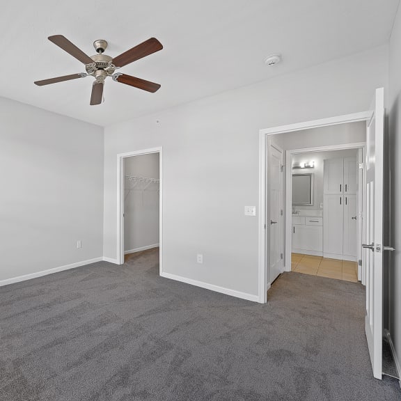 Thumbnail 14 of 19 a bedroom with a ceiling fan and a door to a hallway at Monmouth Row Apartments, Newport, KY