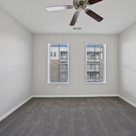 Thumbnail 13 of 19 an empty room with a ceiling fan and two windows at Monmouth Row Apartments, Newport