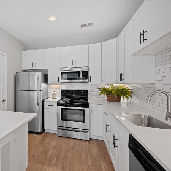Thumbnail 4 of 15 a renovated kitchen with white cabinets and stainless steel appliances at Monmouth Row Apartments, Newport, KY