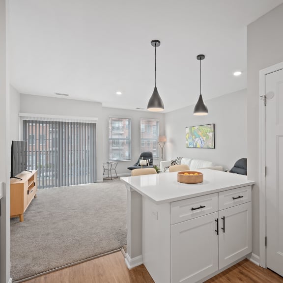 Thumbnail 6 of 15 an open kitchen and living room with white cabinets and a white counter top at Monmouth Row Apartments, Newport, 41071