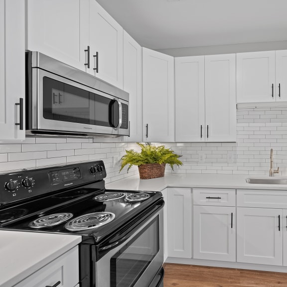 Thumbnail 3 of 15 a white kitchen with black appliances and white cabinets at Monmouth Row Apartments, Kentucky