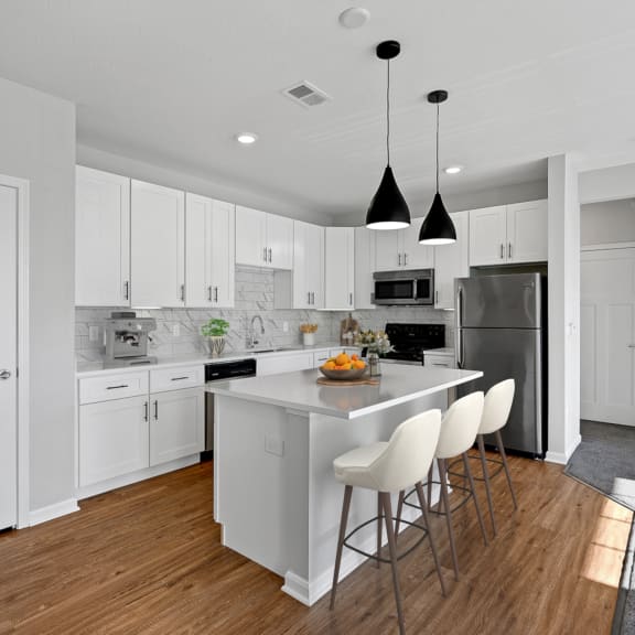 Thumbnail 3 of 7 a large white kitchen with an island and white chairs at Monmouth Row Apartments, Newport, KY