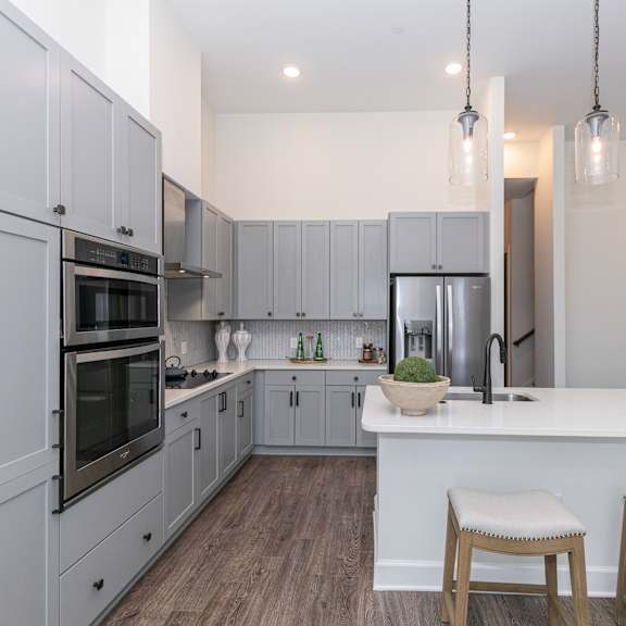 Thumbnail 2 of 8 A modern kitchen with a white island and grey cabinets.