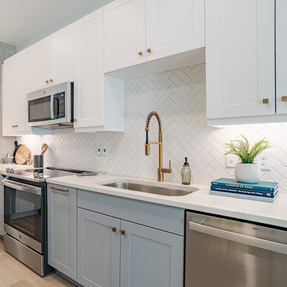 modern kitchen with herringbone tile backsplash and blue cabinets at the yancey apartments, north carolina