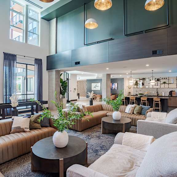 double height clubhouse with lounge seating and kitchen at the yancey apartments, charlotte, 28217