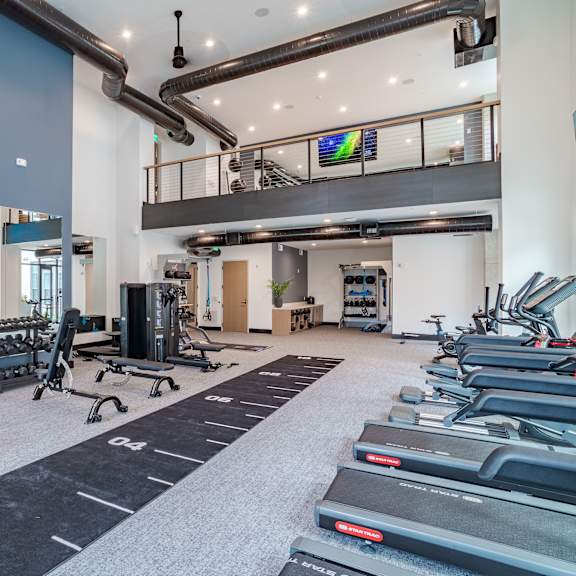 two story fitness center with cardio and strength training equipment at the yancey apartments, north carolina