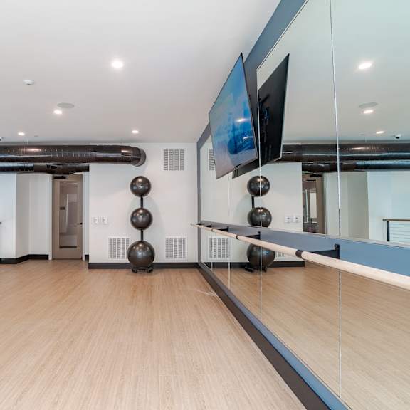 upper level fitness studio with mirrored wall and wood flooring at the yancey apartments, charlotte, 28217