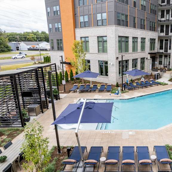 pool deck with lounge chairs and blue umbrellas at the yancey apartments, charlotte, 28217