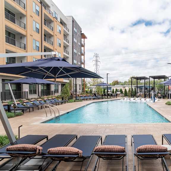 pool area with large umbrellas and surrounding lounge chairs at the yancey apartments, charlotte, north carolina