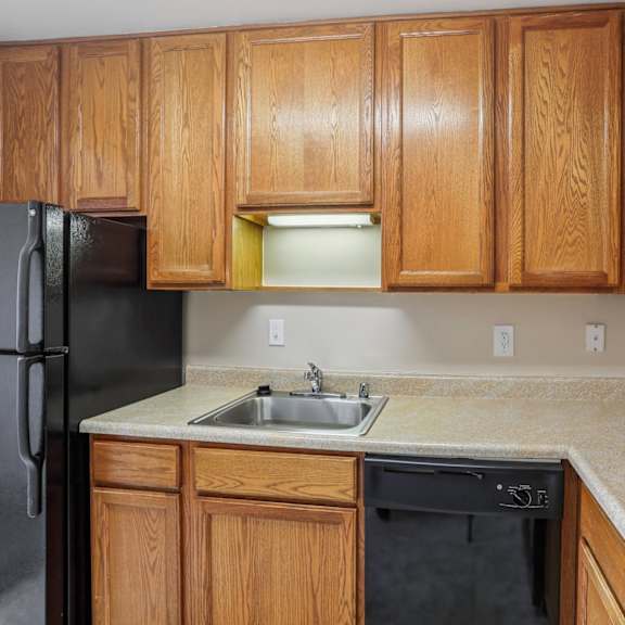 a kitchen with wooden cabinets and a black refrigerator