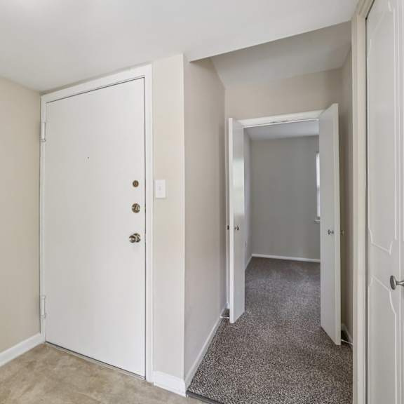 a white door with a handle and a lock is in a room with a carpet.