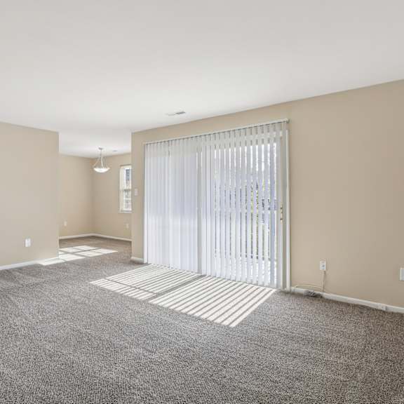 a spacious room with a carpeted floor and a sliding glass door.