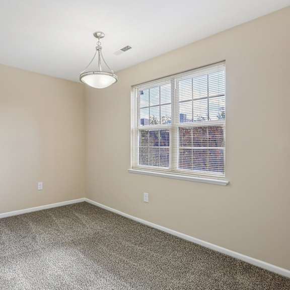 a room with a window and a hanging light fixture.