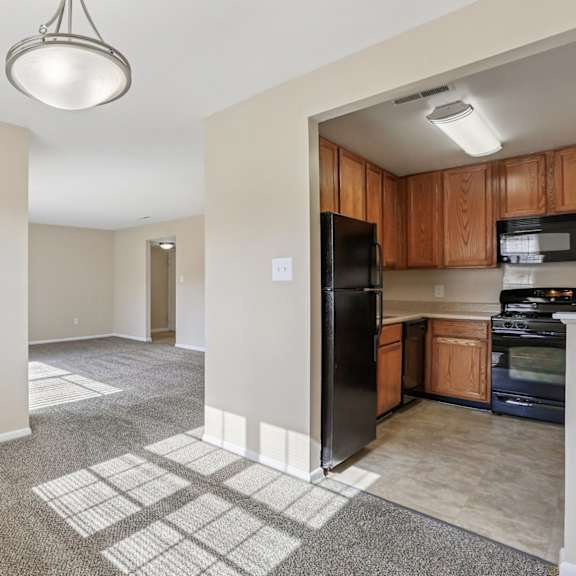 a kitchen area with a black refrigerator and a microwave on top of the counter.