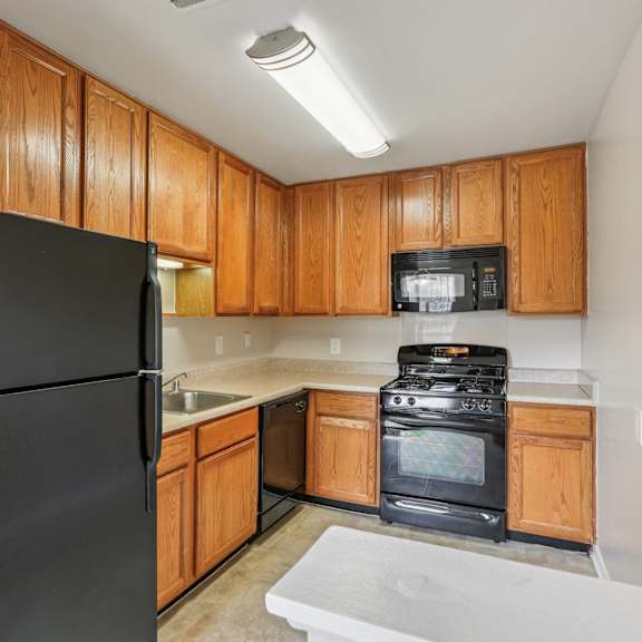 a black refrigerator is in a kitchen with wooden cabinets.