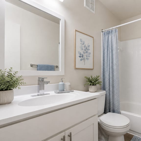 a white bathroom with a toilet, sink, and bathtub.