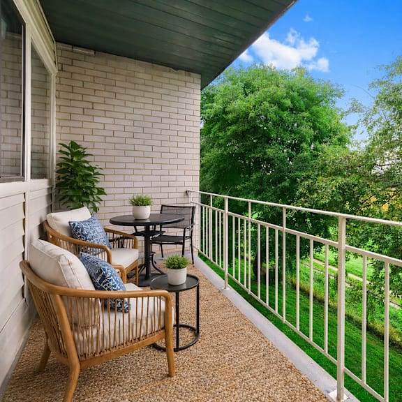 a balcony with a table and chairs overlooking a green lawn.
