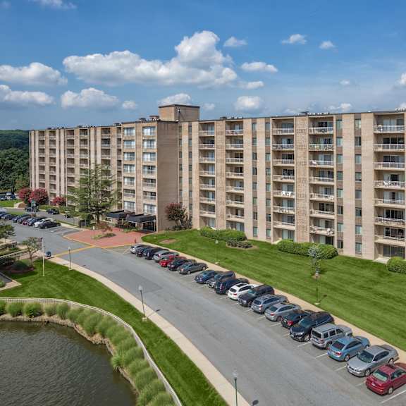 a large apartment building with a parking lot in front.