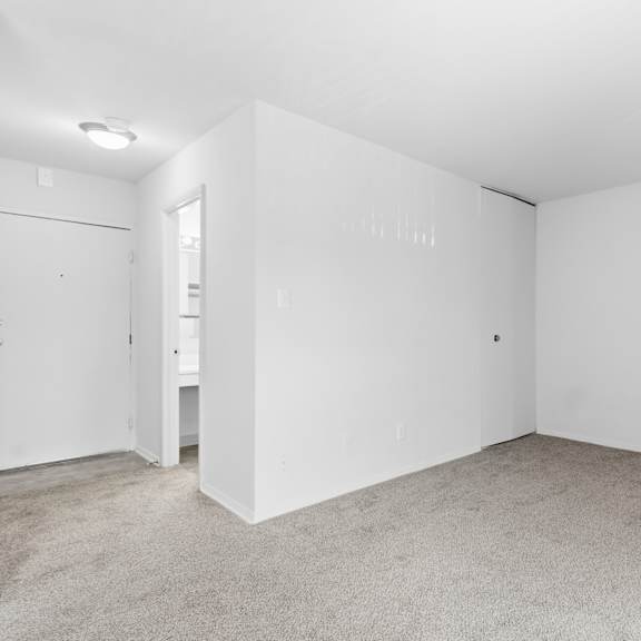 a white room with a carpeted floor and a door on the left.