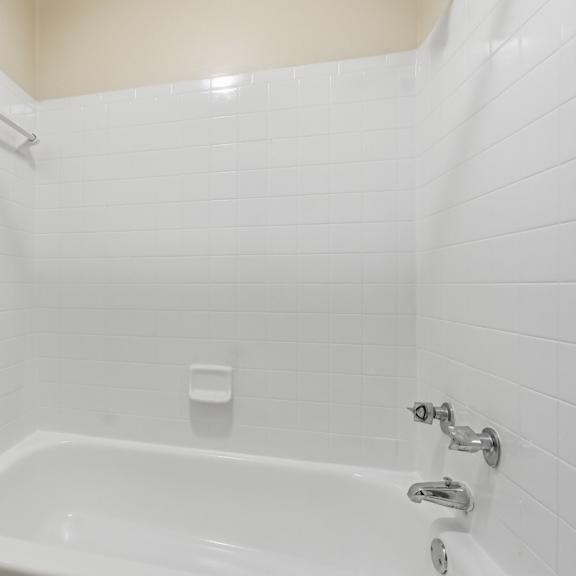 a white bathroom with a tub and toilet.