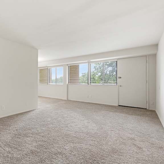 a large, empty room with carpeted flooring and white walls.